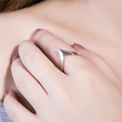 Silver wishbone V ring on a hand, open V tip shape at the finger.